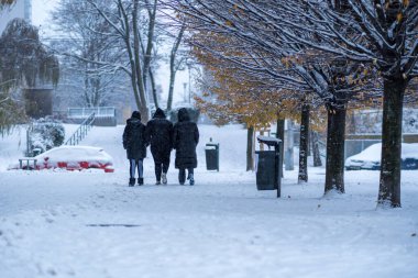 Brno, Çek Cumhuriyeti - 2 Aralık 2023: Kar fırtınası sırasında siyah kapüşonlu ceketli üç kadın karlı bir merdivenden aşağı iniyor. Şehirde karlı kış havası.