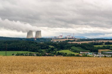 Arka planda Güney Bohemya 'daki Temeln nükleer enerji santralinin bacaları olan orman ve tarlaların manzarası.