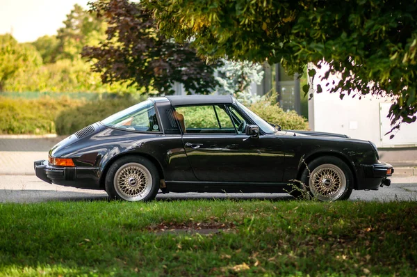 80 'lerden kalma siyah bir Porsche 911 spor arabası sokağa park edilmiş. Klasik bir arabanın yan görüntüsü.