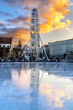 Brno, Czech Republic - 18 December 2023: Observation wheel for tourists in winter in the city center. Empty ice surface on ice rink.