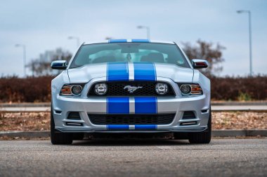 Brno, Çek Cumhuriyeti - 31 Aralık 2023: Mavi folyo hızlı şeritli gümüş hızlı bir Ford Mustang spor arabası bir otoparka park edilmiştir. Arabanın ön kısmının görüntüsü.