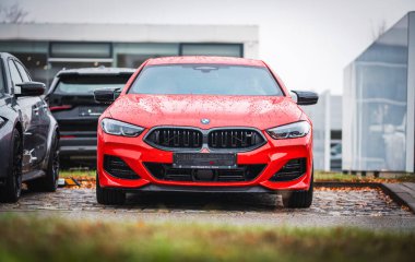 Brno, Çek Cumhuriyeti - 25 Kasım 2023: Siyah ızgaralı kırmızı BMW M spor arabasının ön görüntüsü. Sonbaharda yağmur damlalarından ıslanan araba dışarıda..