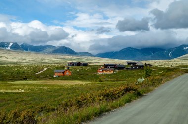 Rondane Ulusal Parkı - Norveç 'in yüksek dağları yakınlarındaki bir çayır arazisinde küçük ahşap evler