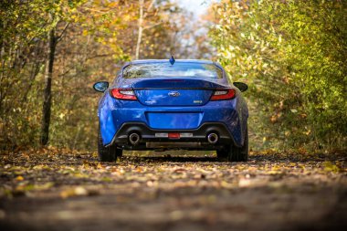 Brno, Çek Cumhuriyeti - 28 Ekim 2023: Hızlı küçük spor araba Subaru BRZ ormanda. Güçlü mavi Japon arabası bir orman yolunda..