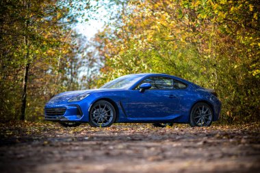 Brno, Çek Cumhuriyeti - 28 Ekim 2023: Hızlı küçük spor araba Subaru BRZ ormanda. Güçlü mavi Japon arabası bir orman yolunda..