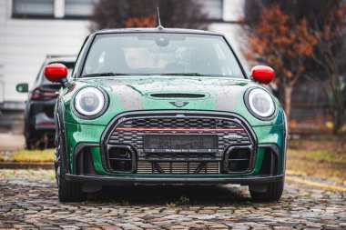 Brno, Çek Cumhuriyeti - 10 Kasım 2023: Yeşil küçük spor araba Mini Cooper yağmurda dışarıda park halinde.