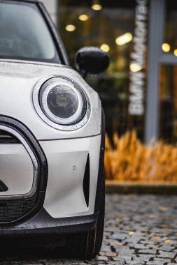 Brno, Çek Cumhuriyeti - 10 Kasım 2023: küçük şık beyaz bir Mini Cooper arabasının ön LED ışığının ayrıntıları. Sonbaharda araba park yeri.