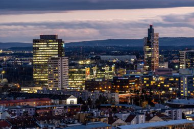 Brno, Çek Cumhuriyeti - 21 Aralık 2023: Şehir merkezinde aydınlatılmış modern binalarla gün batımından sonra gece kenti manzarası.