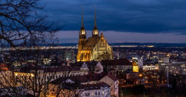 Brno, Çek Cumhuriyeti - 21 Aralık 2023: Aydınlatılmış sokakları ve şehir merkezinde yüksek kuleleri olan katedrali olan gece kenti panoraması. Sokak lambaları olan bir akşam sokağı.