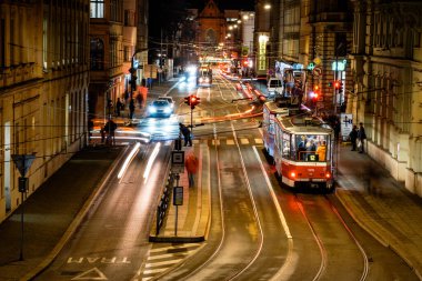 Brno, Çek Cumhuriyeti - 21 Aralık 2023: Tramvay şehrin gece caddesi boyunca raylar boyunca ilerliyor. Trafiği ve insanları olan şehir merkezi. Geceleri sokak lambalarıyla aydınlanıyor..