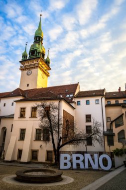 Brno, Çek Cumhuriyeti - 18 Mart 2024: Şehrin merkezindeki eski belediye binasının kulesi. Evlerin arasında, üzerinde Brno yazan küçük bir meydan..