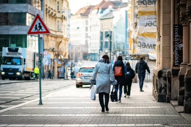 Brno, Çek Cumhuriyeti - 18 Mart 2024: İnsanlar sabah Avrupa 'da eski bir tarihi kentin sokaklarında işe gidiyorlar. Yol işaretine dikkat edin çocuklar..
