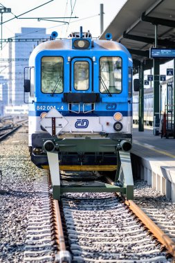 Brno, Çek Cumhuriyeti - 18 Mart 2024: Platformun yanındaki tren istasyonunda mavi beyaz bir lokomotif duruyor. Şehirdeki bir istasyonda yolcu bekleyen bir tren..