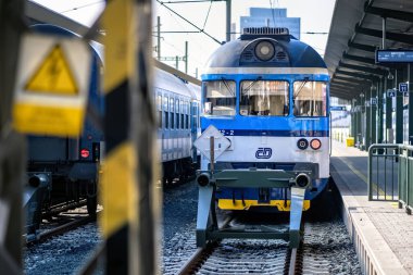 Brno, Çek Cumhuriyeti - 18 Mart 2024: Platformun yanındaki tren istasyonunda mavi beyaz bir lokomotif duruyor. Şehirdeki bir istasyonda yolcu bekleyen bir tren..