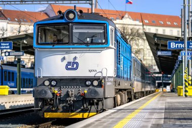 Brno, Çek Cumhuriyeti - 18 Mart 2024: Platformun yanındaki tren istasyonunda mavi beyaz bir lokomotif duruyor. Şehirdeki bir istasyonda yolcu bekleyen bir tren..