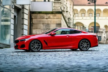 Brno, Çek Cumhuriyeti - 28 Mart 2024: Pahalı spor lüks kırmızı BMW M8 arabası caddenin dışındaki şehir merkezinde park halinde..