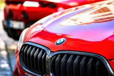 Brno, Çek Cumhuriyeti - 25 Mart 2024: Kırmızı bir arabanın kaputundaki BMW logosunun ayrıntıları. Arabanın ön tarafında radyatör ızgarası var..