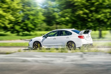 Brno, Çek Cumhuriyeti - 16 Mayıs 2024: Beyaz Subaru WRX STI spor arabası. Subaru ağaçlar boyunca hızla gidiyor..