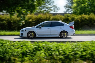 Brno, Çek Cumhuriyeti - 16 Mayıs 2024: Beyaz Subaru WRX STI spor arabası. Subaru ağaçlar boyunca hızla gidiyor..
