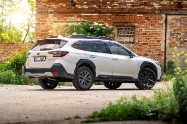 Brno, Çek Cumhuriyeti - 2 Haziran 2024: Beyaz modern Subaru Outback SUV eski bir sanayi binasının tuğla duvarının yanında park halinde..