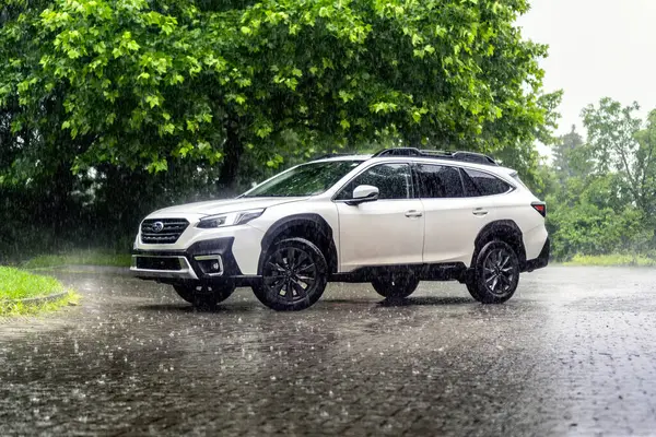 Brno, Çek Cumhuriyeti - 15 Haziran 2024: Beyaz aile SUV Subaru Outback sağanak yağmur altında sokakta duruyor.