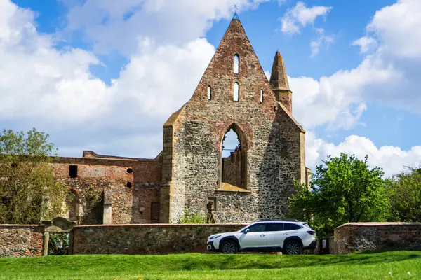 stock image Dolni Kounice, Czech Republic - May 18, 2024: A white Subaru Outback family SUV stands outside in a meadow across the old demolished Rosa Coeli Cathedral.