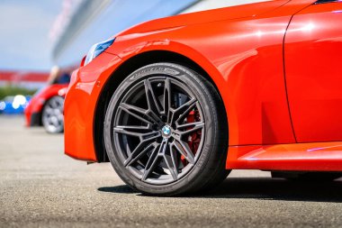Brno, Çek Cumhuriyeti - 10 Eylül 2024: BMW M2 spor kırmızı araba üzerinde ön tekerlek ve BMW logosu ayrıntıları.
