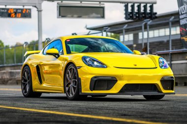 Brno, Çek Cumhuriyeti - 24 Eylül 2024: Sarı spor Porsche 911 bir yarış pistinin önüne park edildi. Dışarıda lüks hızlı araba var..