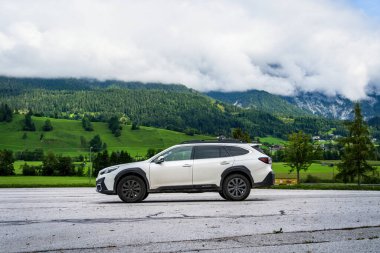 Schladming, Avusturya - 22 Ağustos 2024: Dağlardaki bir otoparkta beyaz aile SUV Subaru Outback. Avusturya Alpleri ile 4x4 'lük bir yolculuk..