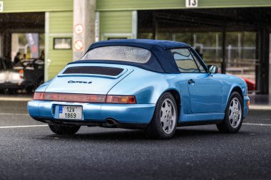 Brno, Çek Cumhuriyeti - 24 Eylül 2024: Mavi eski bir Porsche 911 modeli 964 spor araba bir yarış pistinin çukurlarında park halinde..