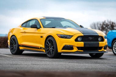 Brno, Çek Cumhuriyeti - 31 Aralık 2023: Hızlı spor araba Ford Mustang dışarıda otoparkta. Siyah folyo şeritli sarı bir araba..