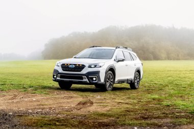 Brno, Çek Cumhuriyeti - 7 Ekim 2024: Beyaz bir Subaru Outback off-road otomobili sabah sisi altında çimlerin üzerinde duruyor. Aile cipi sonbaharda açık havada..
