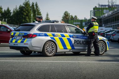 Brno, Çek Cumhuriyeti - 15 Ekim 2024: BMW 5 hızlı polis arabası dışarıda park yerinde duruyor. Bir polis, ekip arabasının yanında duruyor. Çek polisi..