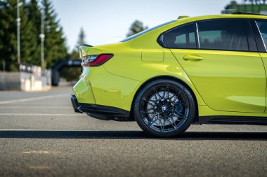 Brno, Çek Cumhuriyeti - 18 Ekim 2024: BMW M3 hızlı lüks araba G80 sarı renkli. Arka tekerlek ve ışık ayrıntıları.