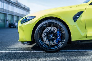 Brno, Çek Cumhuriyeti - 18 Ekim 2024: BMW M3 hızlı lüks araba G80 sarı renkli. Ön tekerlek ve ışık detayı.