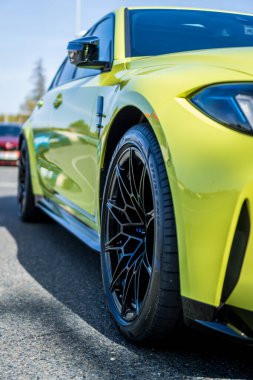 Brno, Çek Cumhuriyeti - 18 Ekim 2024: BMW M3 hızlı lüks araba G80 sarı renkli. Ön tekerlek ve ışık detayı.