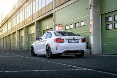 Brno, Çek Cumhuriyeti - 15 Ekim 2024: Beyaz spor BMW M2 bir garaj evinin önündeki yolda. Otoparktaki hızlı Alman arabası..