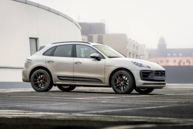 Brno, Çek Cumhuriyeti - 2 Aralık 2024: Gri Porsche Macan spor cipi bir mağazanın çatısına park edildi. Kirli lüks araba bir otoparkta..