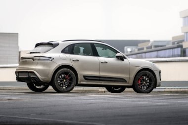 Brno, Çek Cumhuriyeti - 2 Aralık 2024: Gri Porsche Macan spor cipi bir mağazanın çatısına park edildi. Kirli lüks araba bir otoparkta..