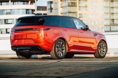 Brno, Çek Cumhuriyeti: 2 Aralık 2024: Lüks, modern geniş SUV Range Rover, şehrin çatı katındaki bir otoparkta yüksek binaların arasına park etti. Pahalı arabalı şehir merkezi.