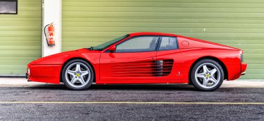 Brno, Çek Cumhuriyeti - 15 Ekim 2024: yarış pistinde kırmızı Ferrari 512 spor araba. Hızlı lüks klasik araba Ferrari Testarossa garajın önüne park etti..