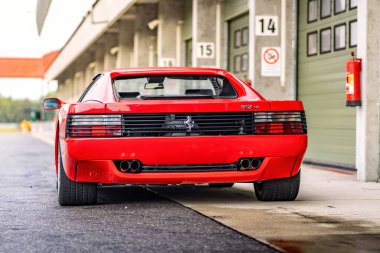 Brno, Çek Cumhuriyeti - 15 Ekim 2024: yarış pistinde kırmızı Ferrari 512 spor araba. Hızlı lüks klasik araba Ferrari Testarossa garajın önüne park etti..