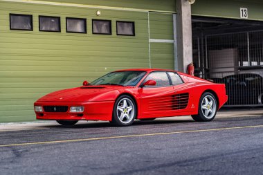 Brno, Çek Cumhuriyeti - 15 Ekim 2024: yarış pistinde kırmızı Ferrari 512 spor araba. Hızlı lüks klasik araba Ferrari Testarossa garajın önüne park etti..