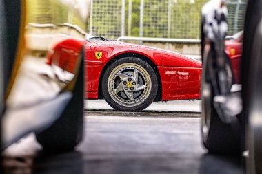 Brno, Çek Cumhuriyeti - 15 Ekim 2024: Kırmızı Ferrari 512 Testarossa spor araba, park halindeki arabaların ön tekerlek detayları.