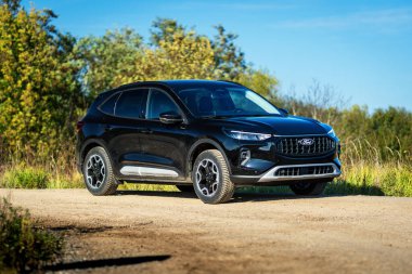 Brno, Çek Cumhuriyeti - 25 Ekim 2024: Siyah Ford Kuga SUV. Tüm tekerden çekişli melez aile arabası. Açık havada toprak bir yolda kesişiyor..