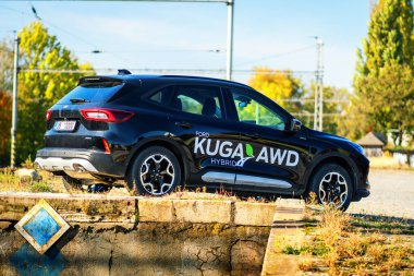 Brno, Czech Republic - October 25, 2024: Black Ford Kuga SUV with advertising sticker. Hybrid family car with all-wheel drive. Crossover outside at the old railway station. clipart