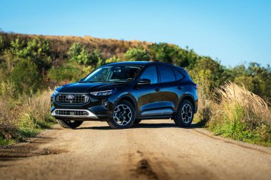 Brno, Çek Cumhuriyeti - 25 Ekim 2024: Siyah Ford Kuga SUV. Tüm tekerden çekişli melez aile arabası. Açık havada toprak bir yolda kesişiyor..