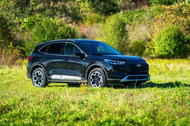 Brno, Çek Cumhuriyeti - 25 Ekim 2024: Siyah Ford Kuga SUV. Tüm tekerden çekişli melez aile arabası. Doğada, çimenli bir çayırda çapraz geçiş..