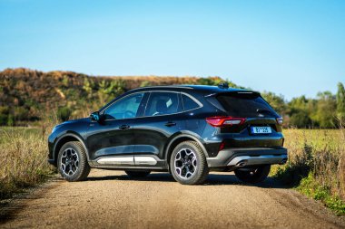 Brno, Çek Cumhuriyeti - 25 Ekim 2024: Siyah Ford Kuga SUV. Tüm tekerden çekişli melez aile arabası. Açık havada toprak bir yolda kesişiyor..
