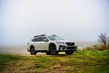 Güney Moravya, Çek Cumhuriyeti - 11 Kasım 2024: Beyaz modern SUV Subaru Outback sonbaharda siste bir arazide duruyor. Ailenin dört çeker off-road arabası..